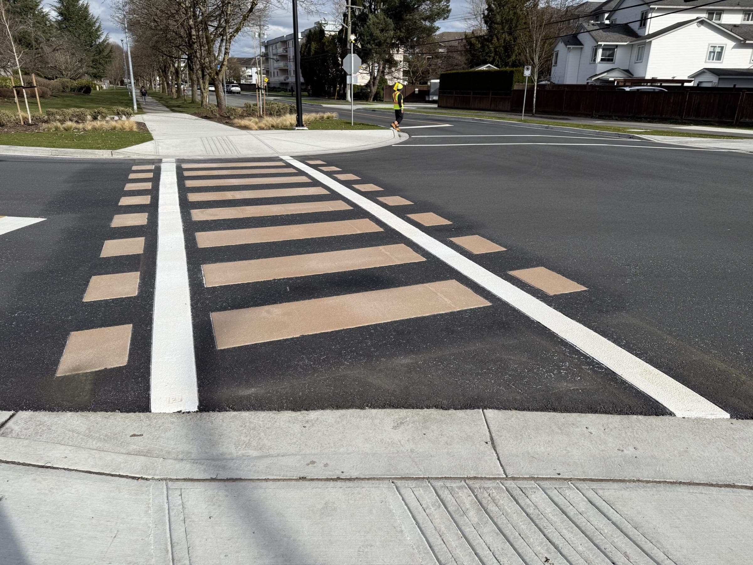 Rail ties in tan TrafficPatternsXD thermoplastic set into dark stamped asphalt — the railroad-inspired crosswalk in the City of Langley