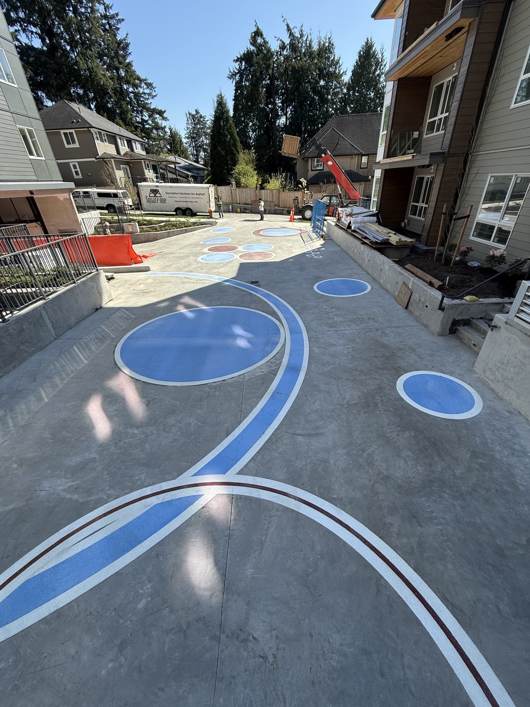 Blue DecoMark circles and sweeping lines set into the concrete courtyard at Red Sol in Coquitlam
