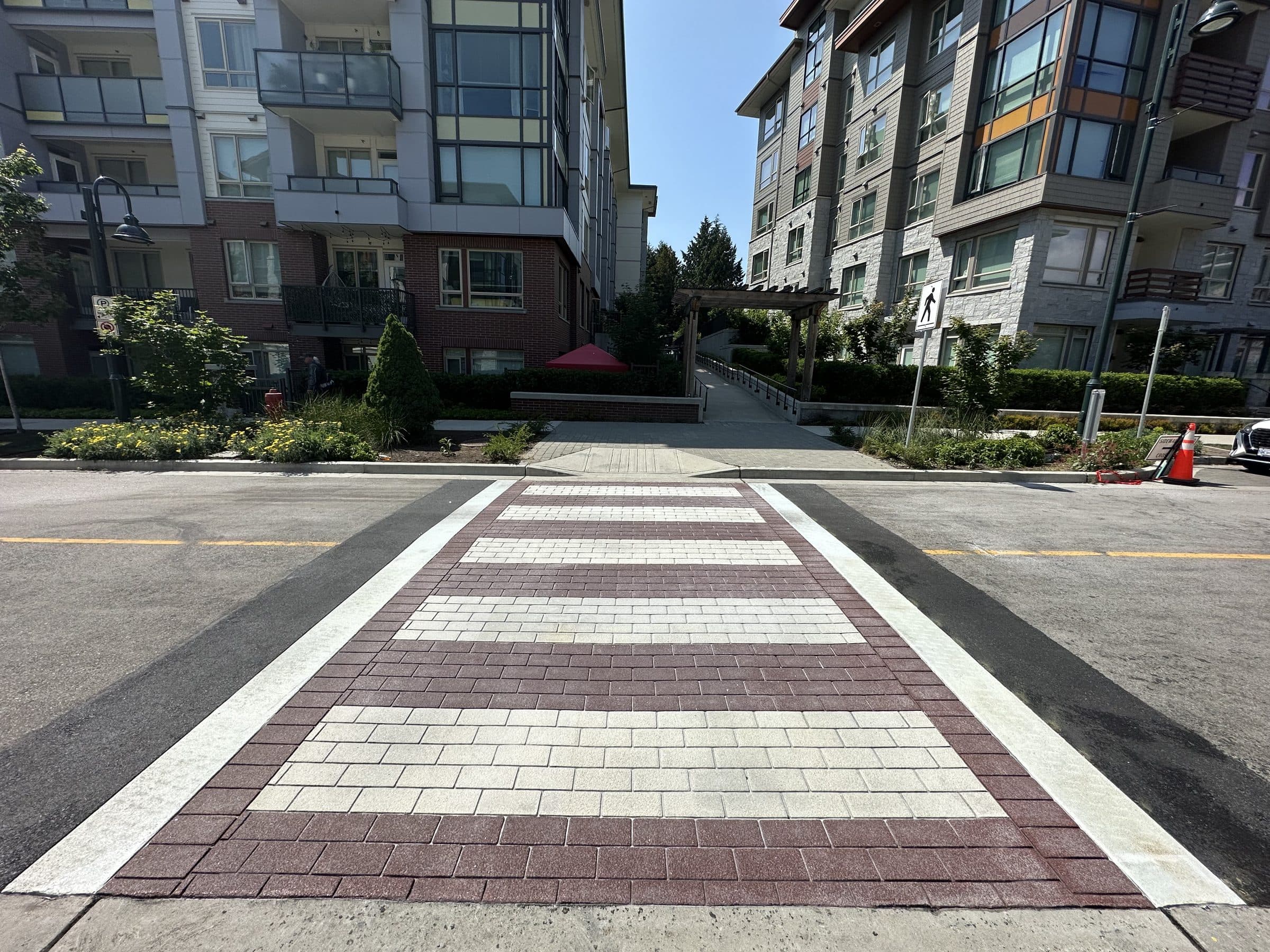 A plum-and-cream brick-pattern TrafficPatternsXD crossing between two townhome blocks on a North Vancouver street, installed by Square One