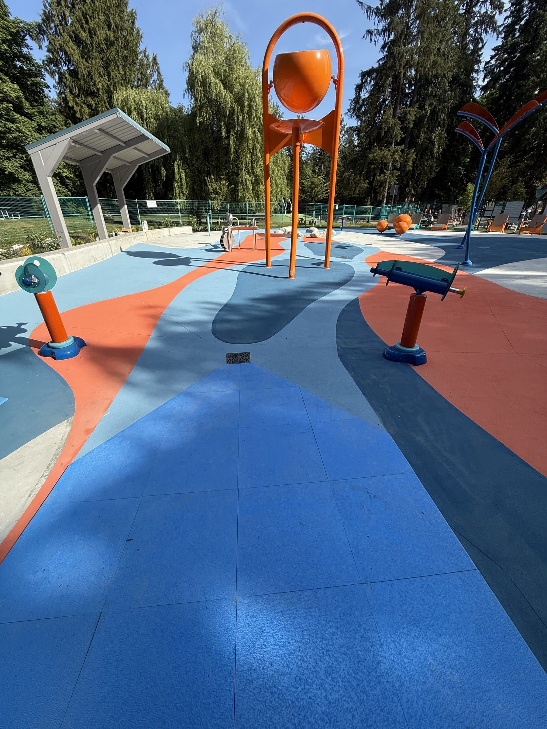 Blue and orange StreetBond around the play features of the spray park in Maple Ridge