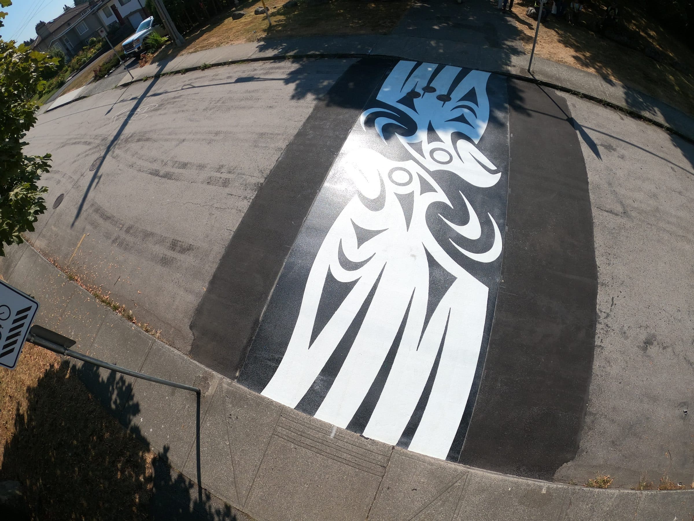 A white thunderbird in DecoMark thermoplastic on the black asphalt of the Union Street greenway in Burnaby, seen from above, installed by Square One