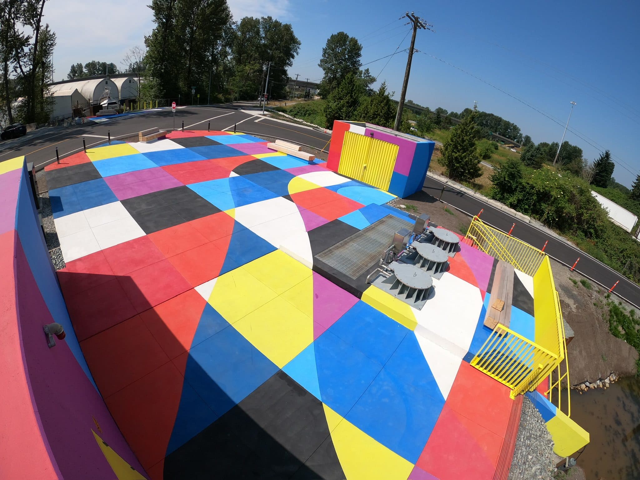 The Boundary Road pump station in New Westminster from above, a quilt of red, blue, yellow, pink, black and white StreetBond squares across the whole plaza, installed by Square One
