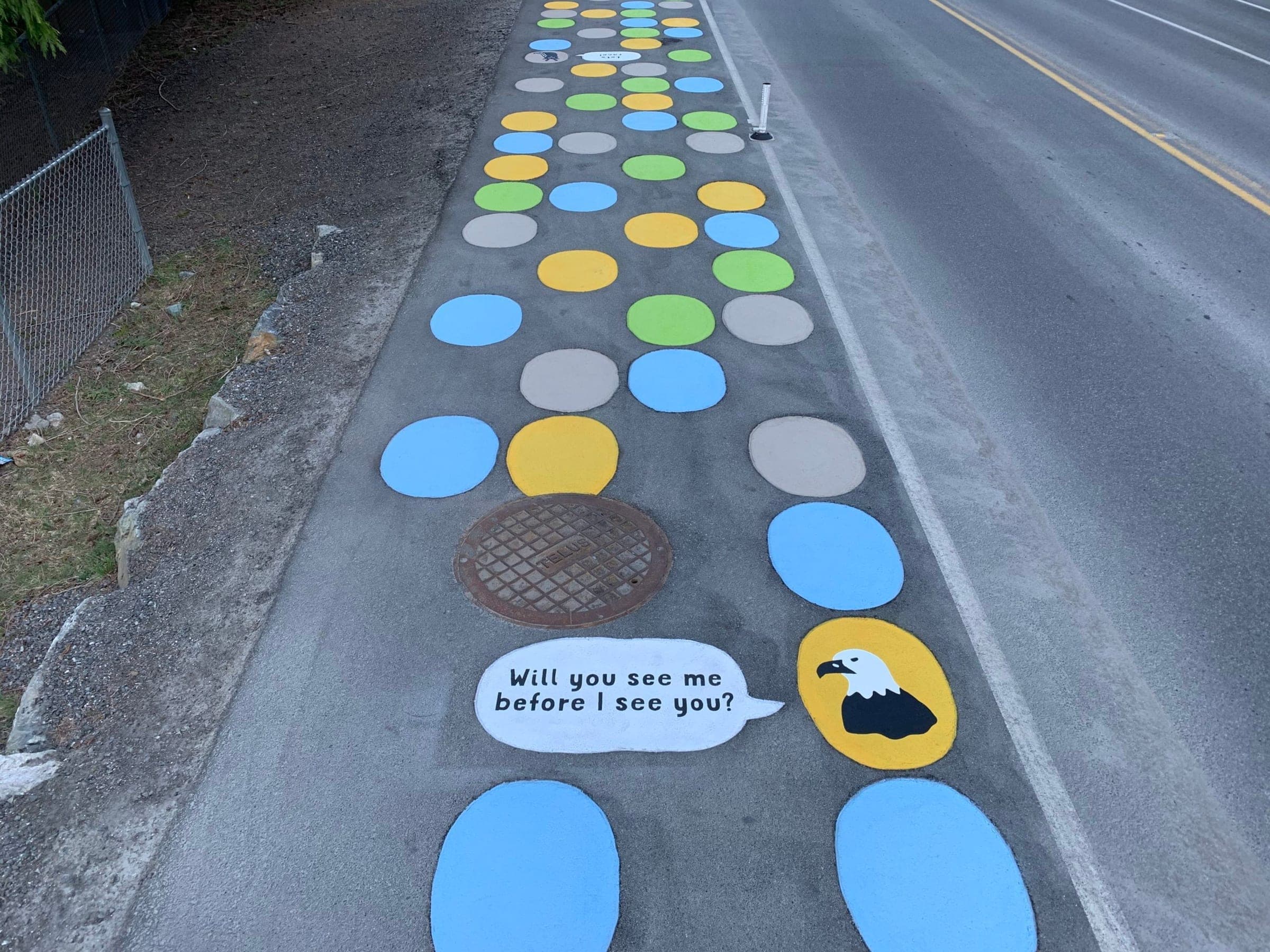 Blue, green, yellow and grey StreetBond dots along the Snug Cove walkway on Bowen Island, with an eagle asking 'Will you see me before I see you?'