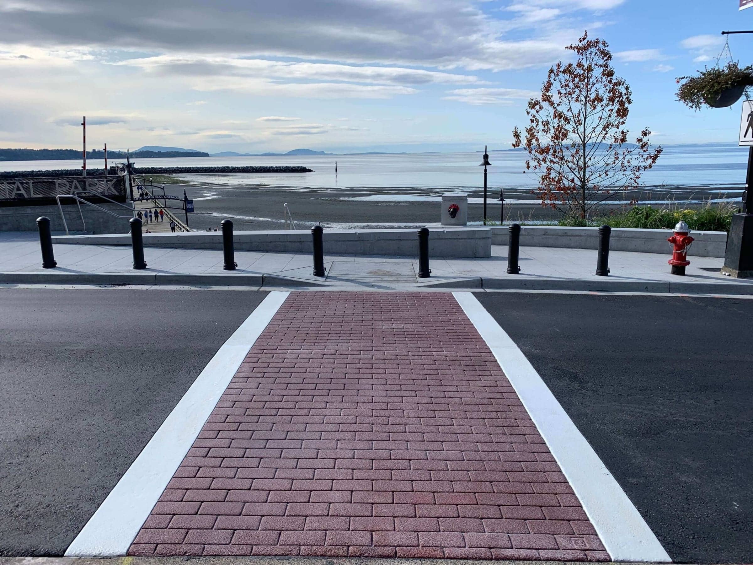 Red TrafficPatternsXD crosswalk leading to the White Rock Pier, Semiahmoo Bay at low tide beyond
