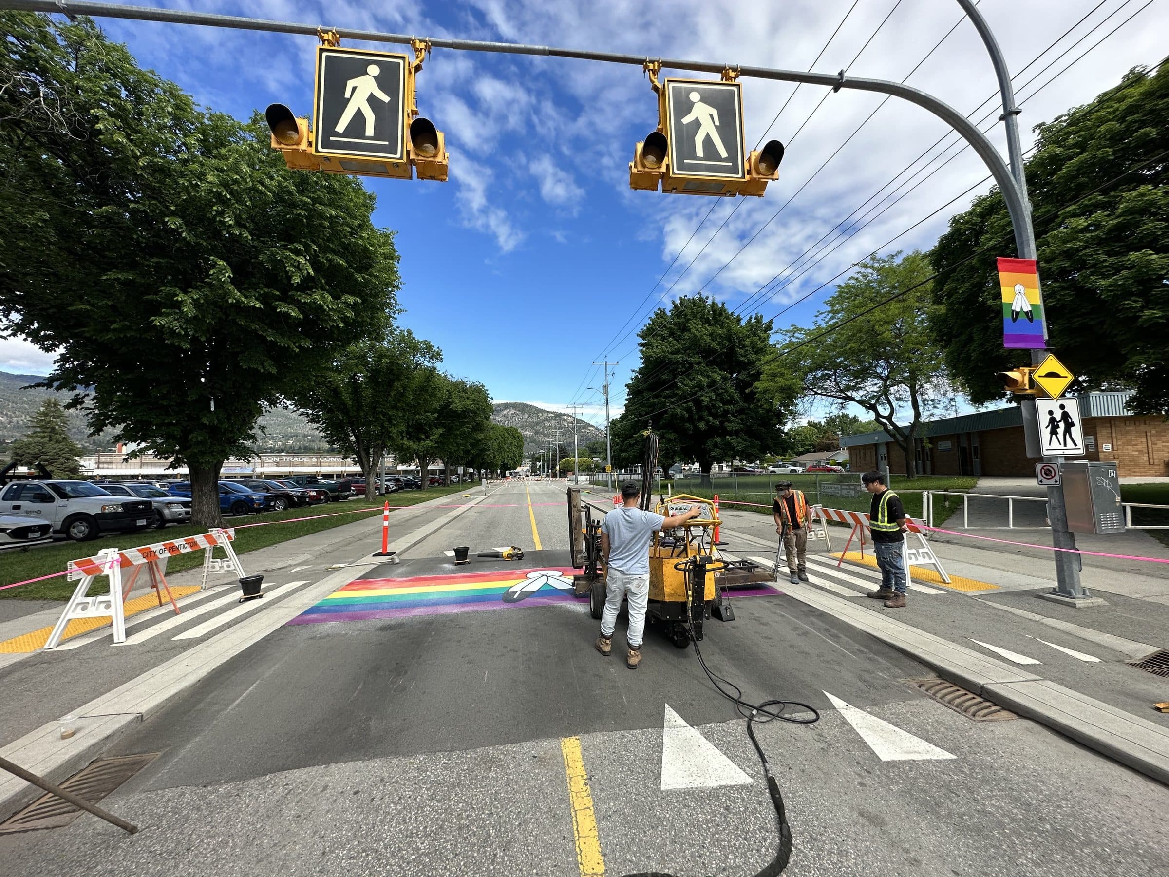 Square One's crew heat-fusing a rainbow crossing under the pedestrian signals in Penticton